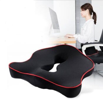 Coussin noir ergonomique avec trou au milieu sur fond blanc. On voit aussi une femme en second plan qui travaille.