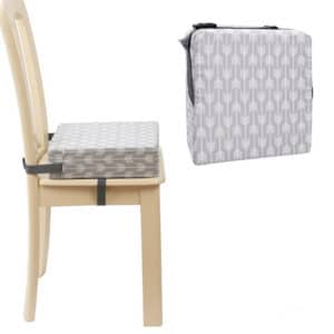 Coussin rehausseur gris montré seul et posé sur une chaise en bois. Fond blanc.