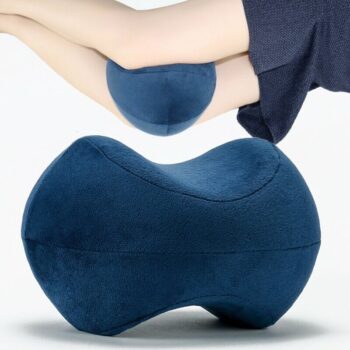 Coussin positionné entre les jambes d'une personne en arrière plan. Devant, on voit le coussin en gros plan sur fond blanc.