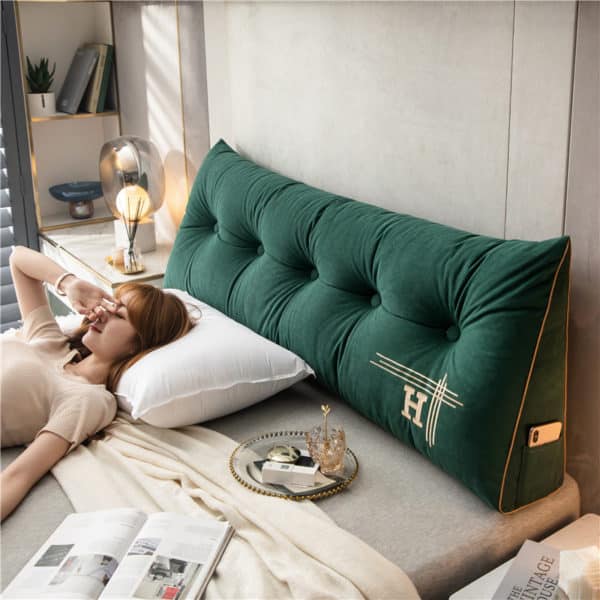 Coussin tête de lit triangulaire et vert avec une femme couchée sur un lit