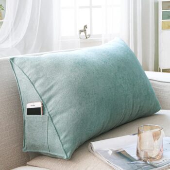 Coussin triangulaire vert clair posé sur un canapé beige.