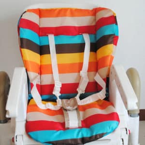 Coussin à bandes multicolores installé sur une chaise haute blanche.