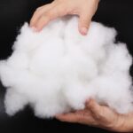 Masse de coton tenu à deux mains sur fond noir.