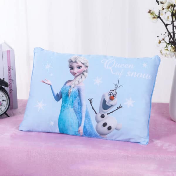 Coussin La reine des neiges avec Elsa et olaf, bleu. LE coussin est posé sur un drap rose devant un rideau