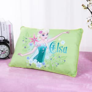 Coussin vert avec Elsa de la reine des neiges. Le coussin est posé sur un drap rose devant un rideau.