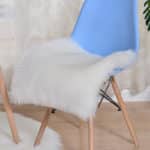 Coussin blanc plat posé sur une chaise bleue.