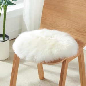 Coussin rond épais en laine blanche posé sur une chaise en bois.