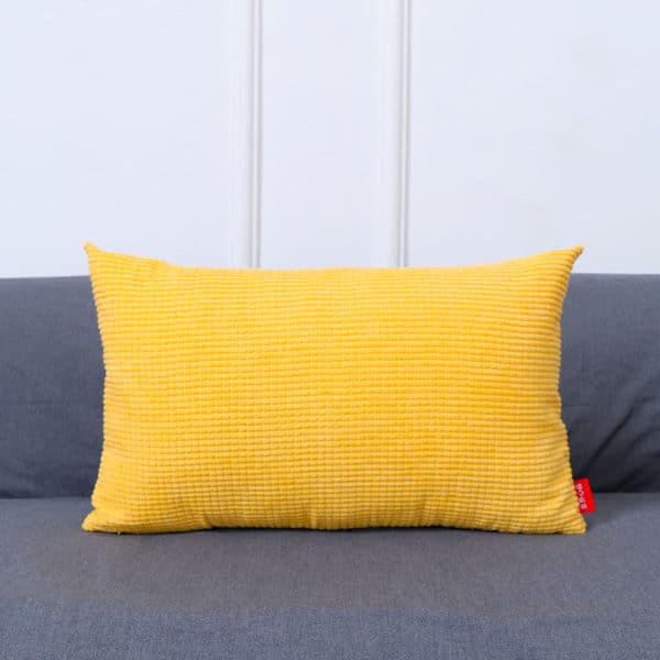 Coussin rectangulaire jaune sur un canapé gris.