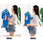 Coussin en peluche kawaii Stitch de forme cylindrique les deux tailles sont tenues par une femme afin de montrer la différence de gabarit entre la taille 60cm et 80cm