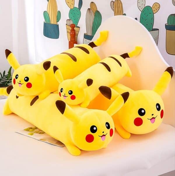 Coussin Pikachu long et de forme cylindrique, les 4 coussins sont de tailles différentes (XS, S, M et L) et sont sur un lit