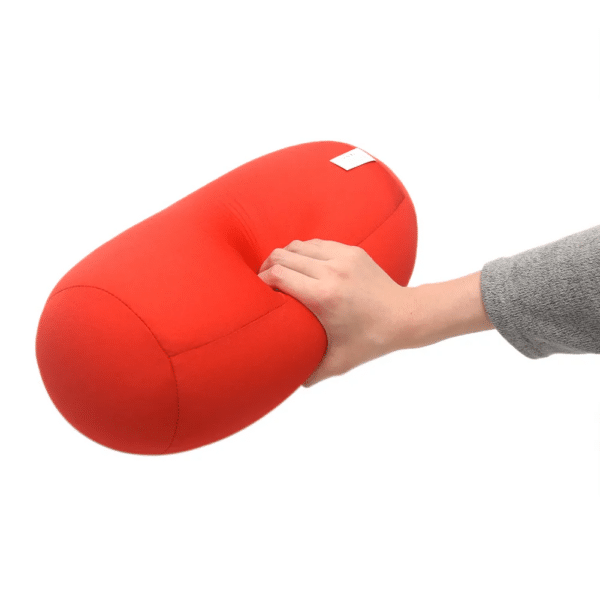 coussin microbilles cylindrique rouge sur un fond blanc une main appuit dessus