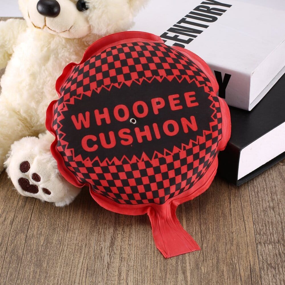 Coussin péteur rouge avec des inscriptions noires posées sur des livres et un ours en peluche blanc