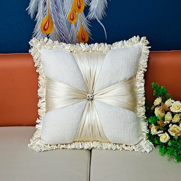 Coussin carré en velours et en lin blanc à motif de fleur posé sur un canapé