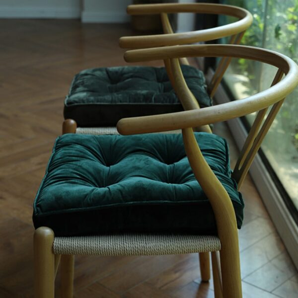 2 coussins épais de couleurs vert foncés, vert canard, posés chacun sur une chaise en bois