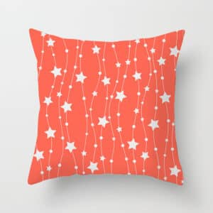 Housse de coussin corail rouge avec des motifs en forme d'étoiles blanches sous un fond gris