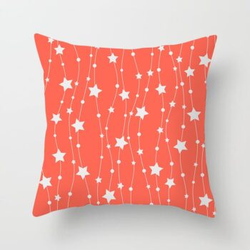 Housse de coussin corail rouge avec des motifs en forme d'étoiles blanches sous un fond gris