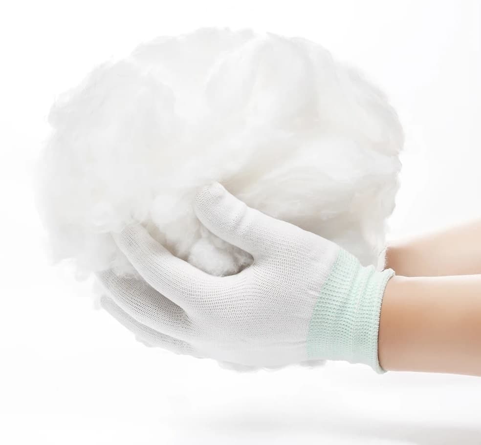Deux mains avec des gants blancs tenant une grosse boule de coton.