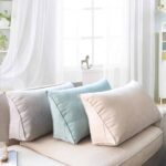 3 coussins de canapé gris clair, vert clair et beige posés sur un canapé beige