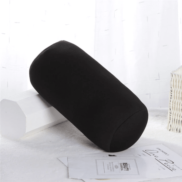 coussin microbilles cylindrique noir posé sur une table et le rebord d'une fênetre