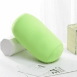 coussin microbilles cylindrique vert pomme posé sur une table et le rebord d'une fênetre