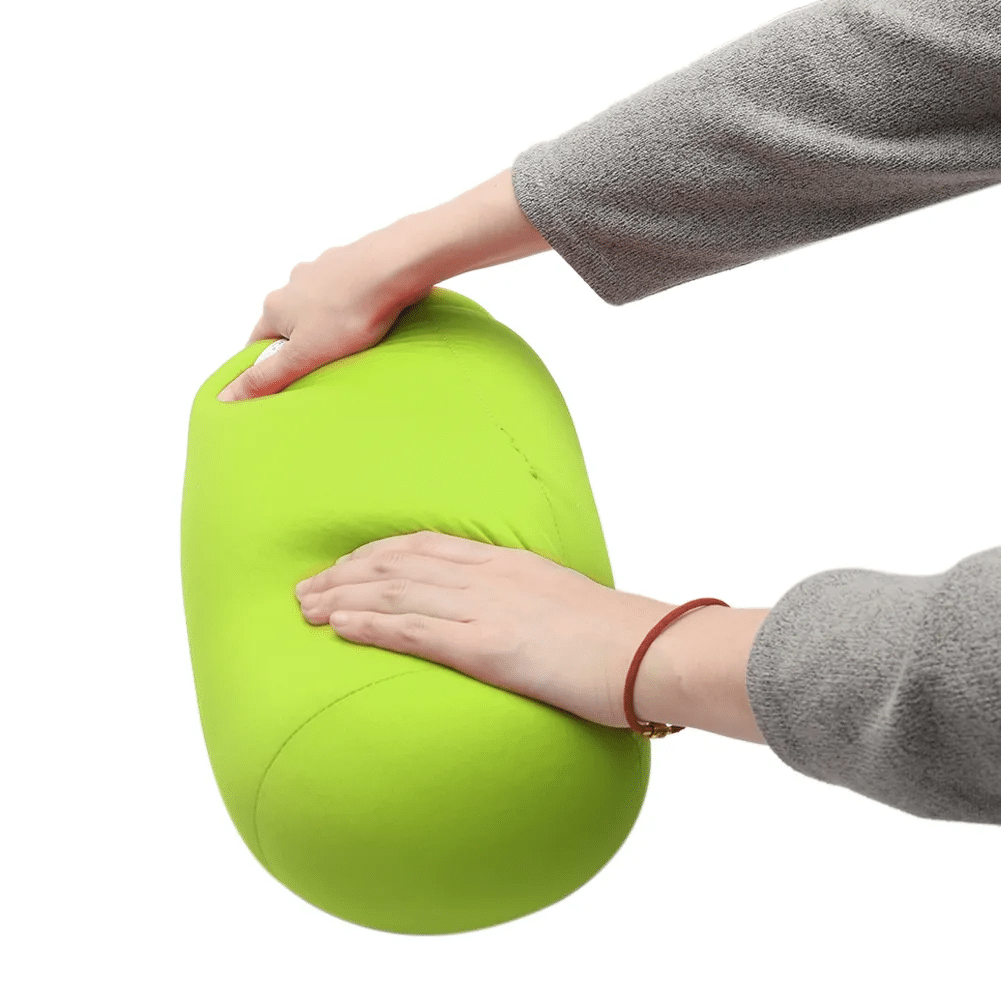 coussin microbilles cylindrique vert pomme sur un fond blanc deux mains appuient dessus