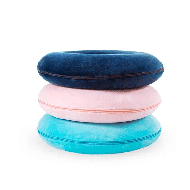 3 coussins coccyx bleu marine, rose ou bleu claire (cyan) l'un sur les autres, derrière un fond blanc.