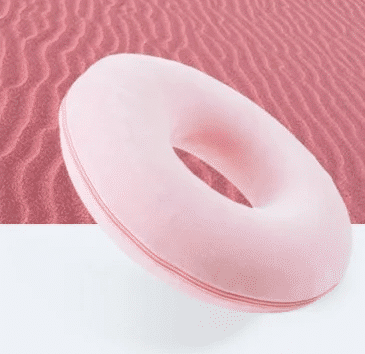 Coussin coccyx circulaire rose sur un fond rouge sable et gris