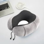 Coussin cervical pour le cou posé sur une table grise avec un clavier d’ordinateur et une tasse de thé blanche à côté