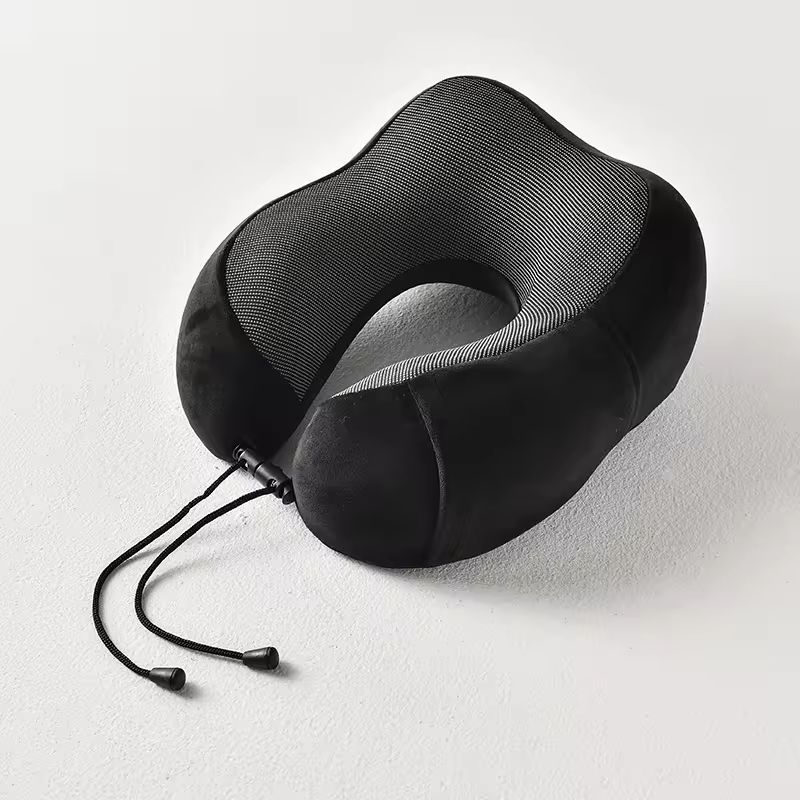 Coussin cervical pour le cou de couleur noir posé sur un sol plâtré