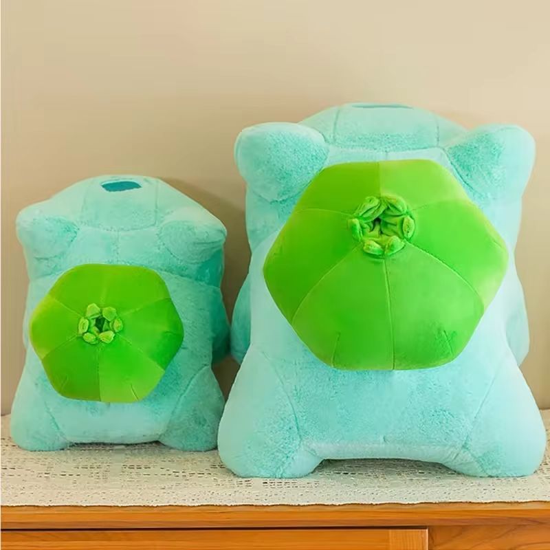 Deux coussins peluche Bulbizarre vu de derrière et posés sur une commode en bois