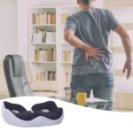 Homme debout à côté d’une chaise et une table de bureau, se tenant le bas du dos avec une main comme pour exprimer une douleur à ce niveau du corps. Femme debout se tenant le bas du dos avec les deux mains comme pour exprimer une douleur à ce niveau du corps. A gauche, le coussin de siège ergonomique de couleur noir en forme de U avec deux trous d'aération et une bande élastique équipée d'une fermeture à boucle pour adapter la taille du coussin à vos fesses.