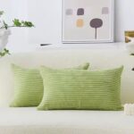 Deux coussins rectangulaires verts pomme en velours côtelé avec des lignes horizontales, posés sur un canapé recouvert d'un tissu clair.